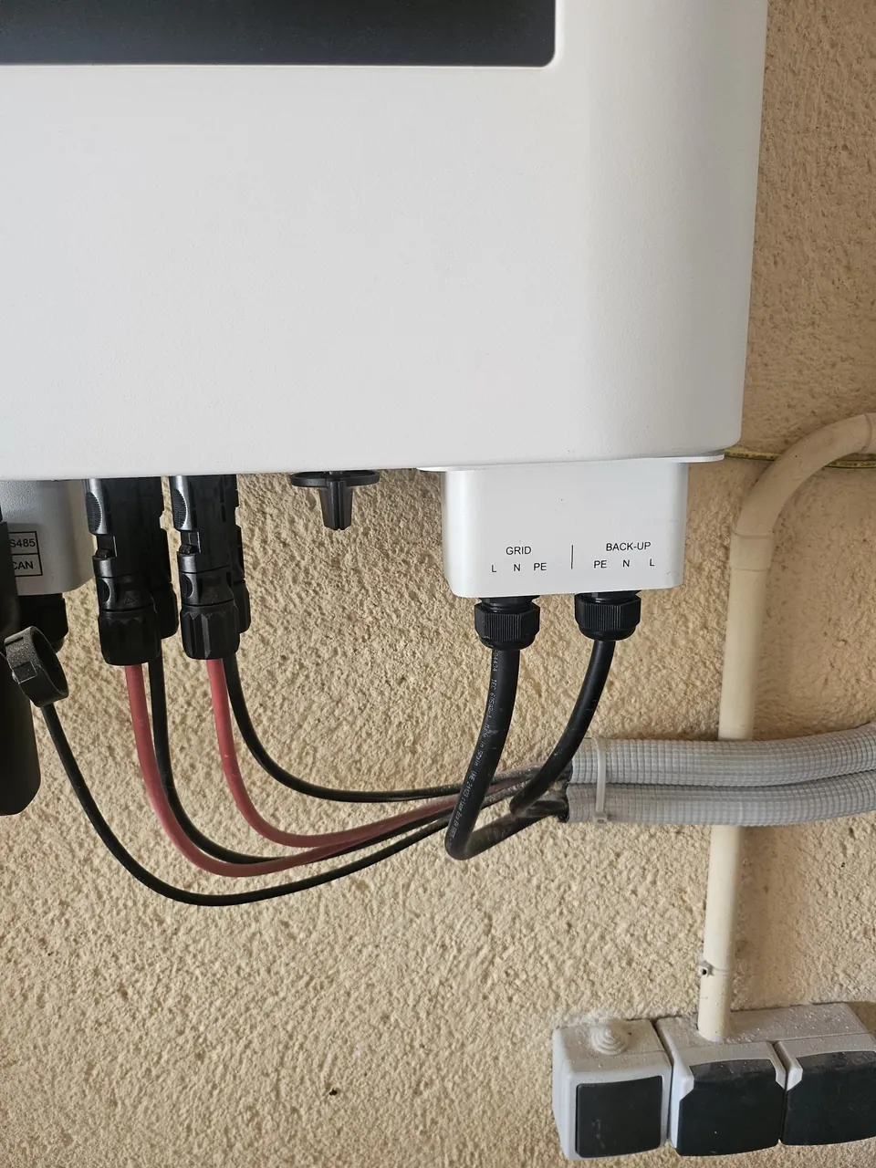 Detail van kabels onder een omvormer bij de aansluitingen Grid en Back-up